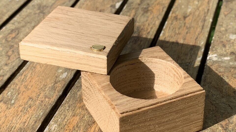 Petite boîte de forme carrée, en chêne, dont le couvercle s'ouvre en pivotant sur un axe situé dans un coin. 